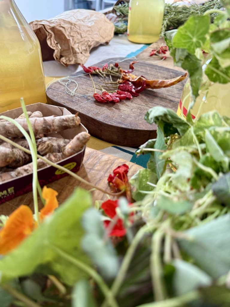 A shot of a table top laid out with chopping boards, apply cyder vinegar, chillies and foliage"